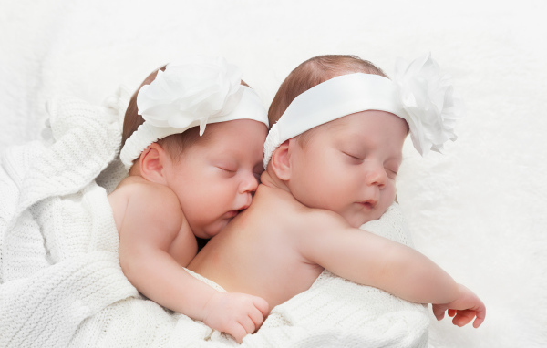 Two sleeping babies with big white flowers on their heads