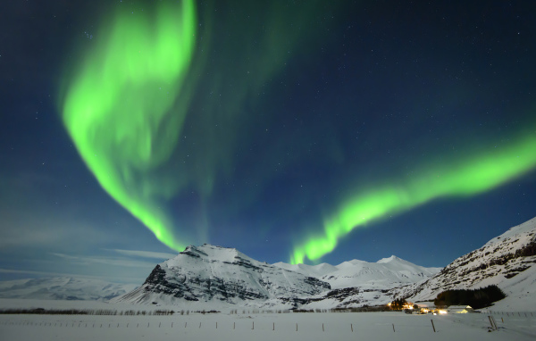 Полярное сияние в небе над заснеженными горами, Исландия