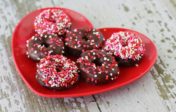 Аппетитные пончики на красной тарелке в форме сердца