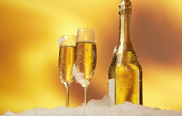 Бутылка шампанского и два фужера стоят на белом снегу