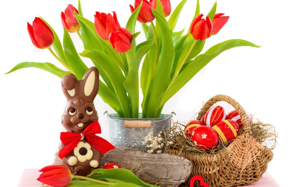 Букет красных тюльпанов на столе с шоколадным кроликом и крашеными яйцами на Пасху