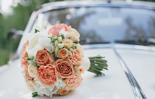 Свадебный букет роз лежит на машине