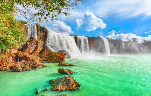 Быстрый водопад стекает со скалы под красивым голубым небом