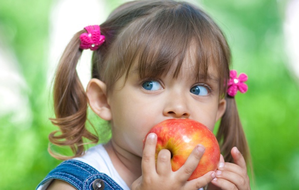 Маленькая голубоглазая девочка с большим яблоком