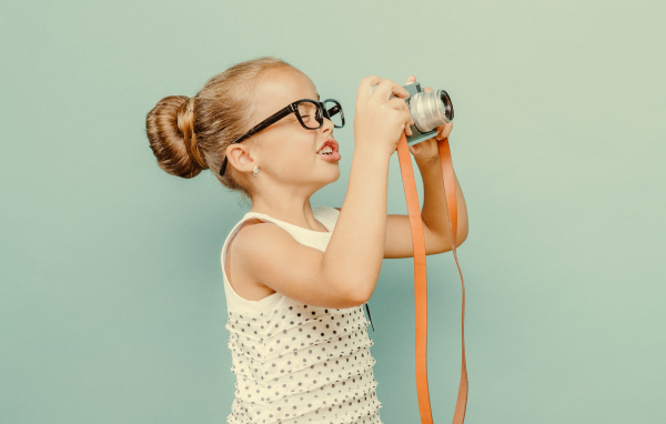Маленькая девочка в очках с фотоаппаратом