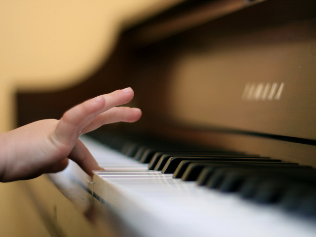     The hand of the child on the piano