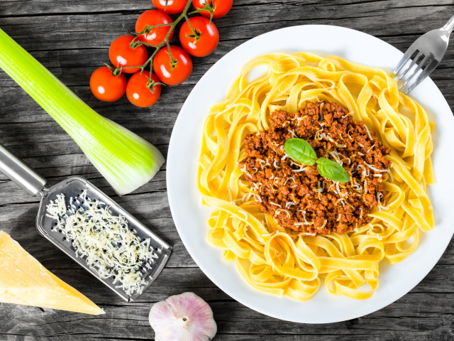 Спагетти на белой тарелке с мясом и сыром