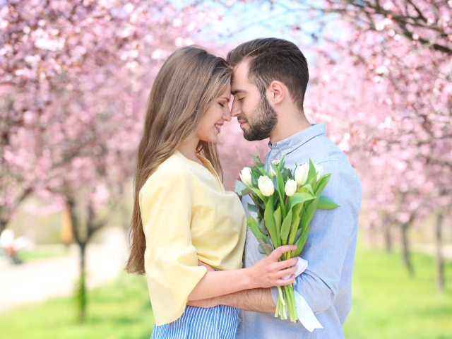A loving couple is standing in a blooming park
