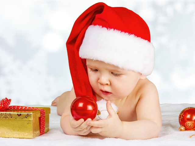 Младенец в красной новогодней шапке с елочными шарами на новый год