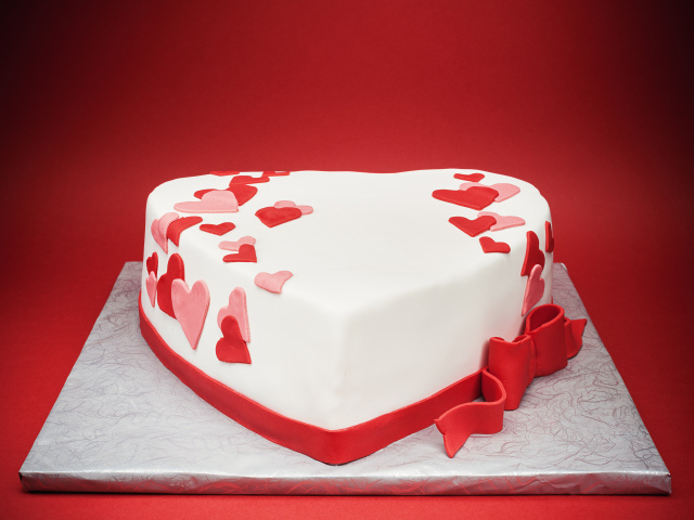 Красивый торт в форме сердца на красном фоне