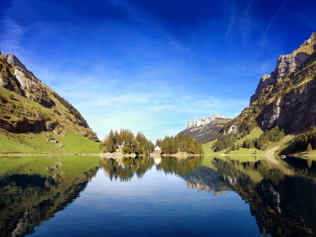 Горы отражаются в воде озера под красивым голубым небом, Швейцария