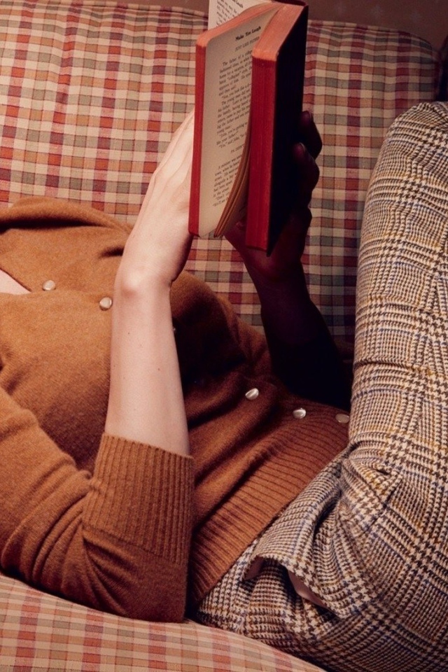 Девушка читает книгу лежа на диване