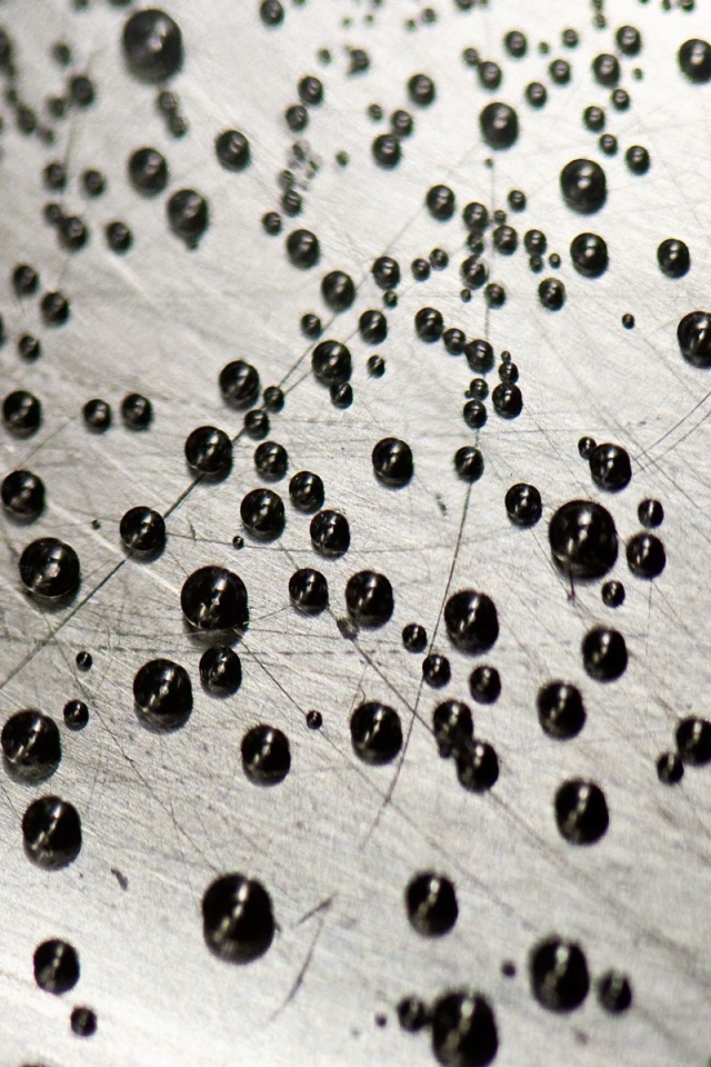 Мелкие черные шарики на серой поверхности