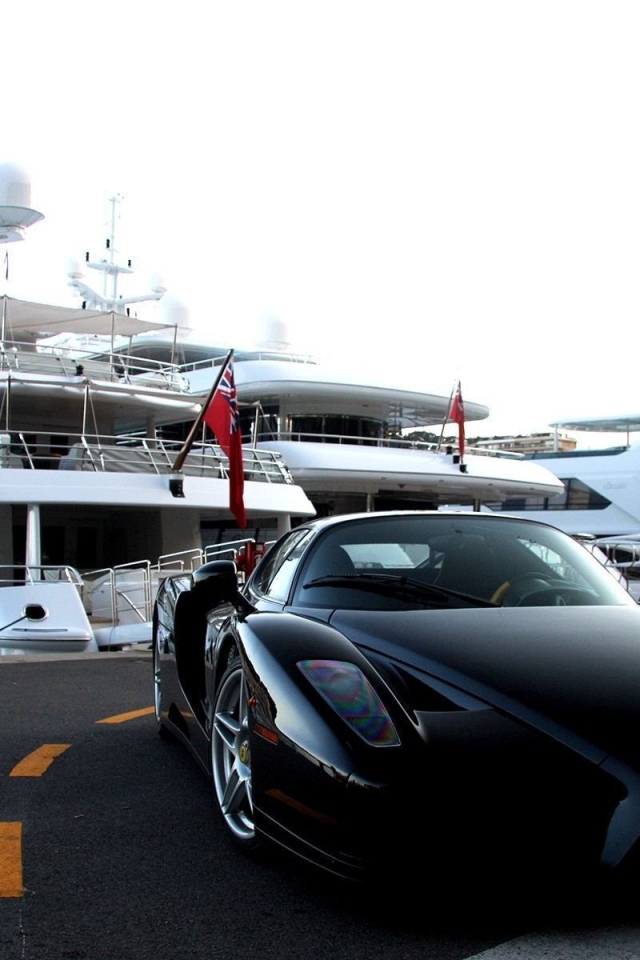 Черный Ferrari на фоне белой яхты