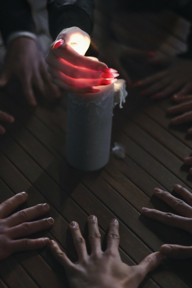 Люди вызывают духа при помощи свечи