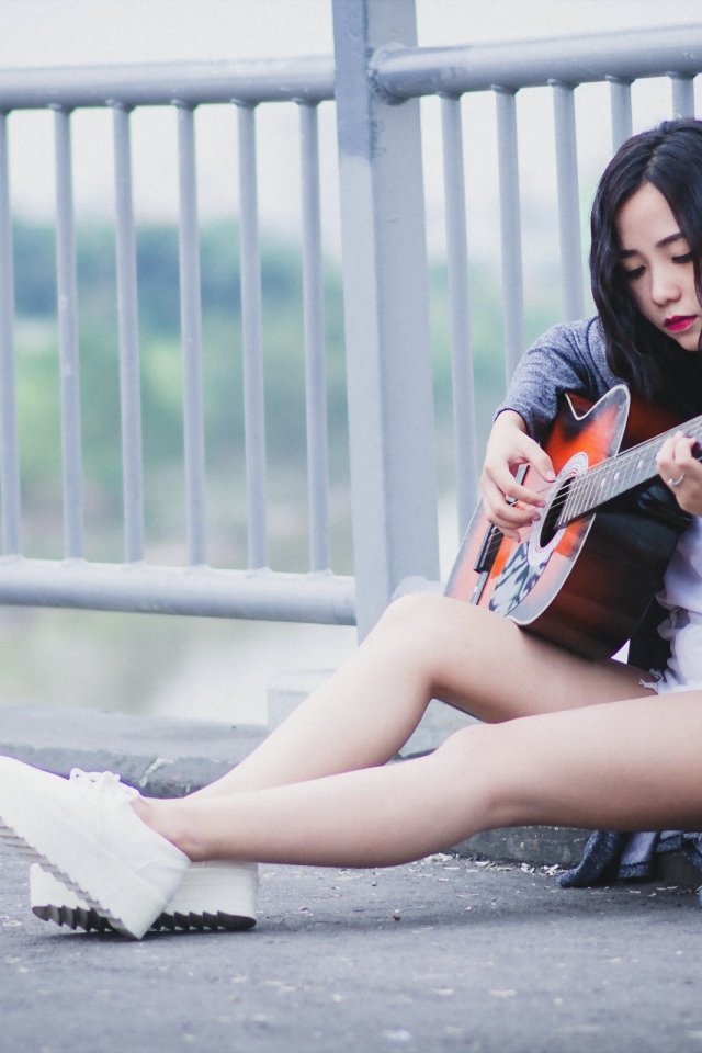 Азиатка брюнетка с гитарой на мосту