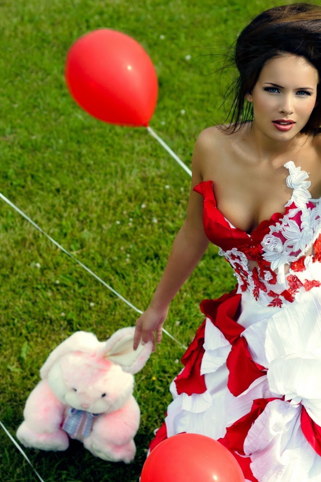 Девушка с игрушкой среди красных воздушных шариков