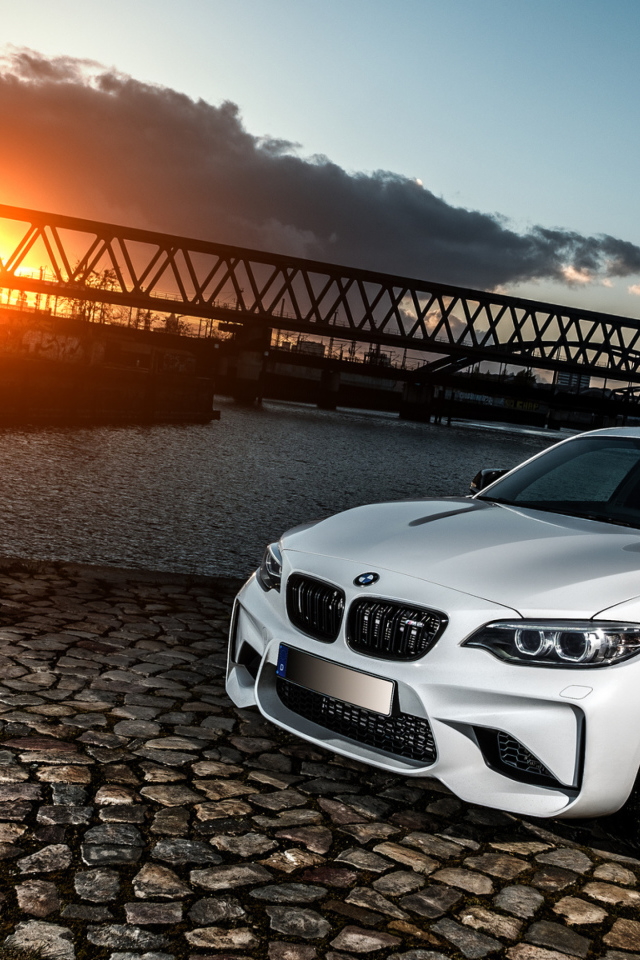 Белый автомобиль BMW M2 на фоне заката 