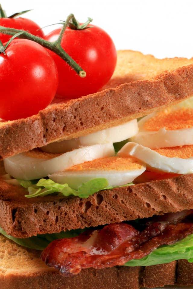 Сэндвич с беконом, яйцами и овощами на белом фоне