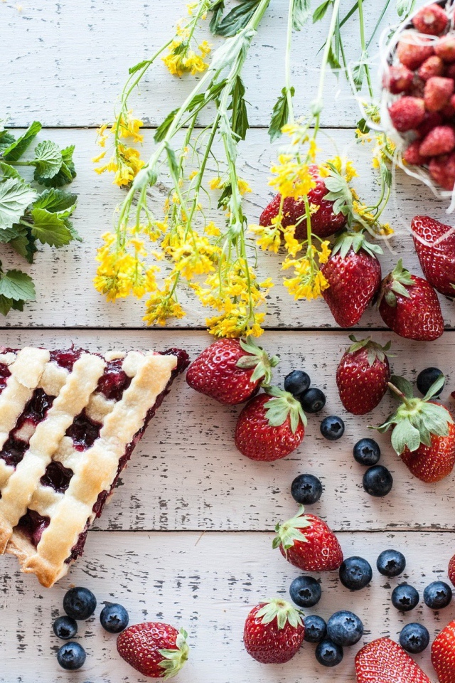 Кусочки пирога на столе с ягодами клубники и черники