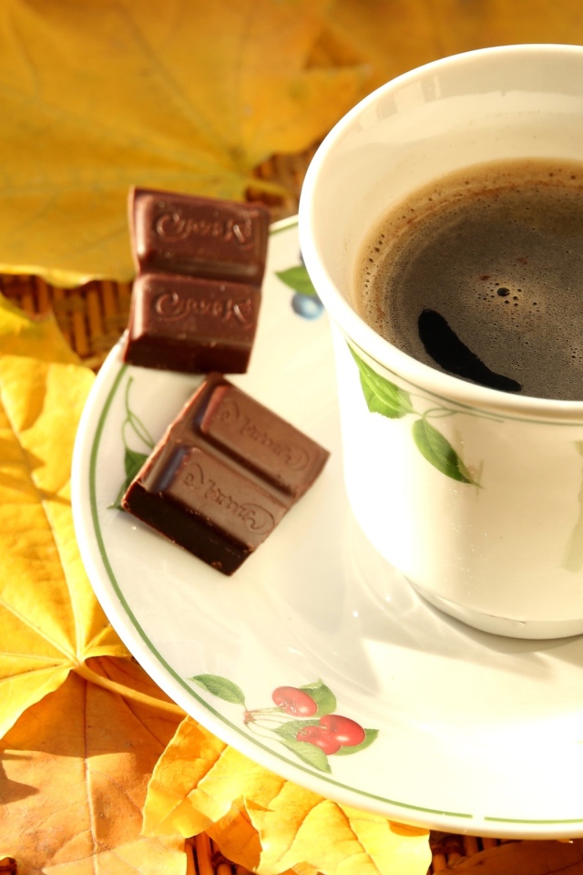 Чашка кофе с черным шоколадом на столе с желтыми листьями
