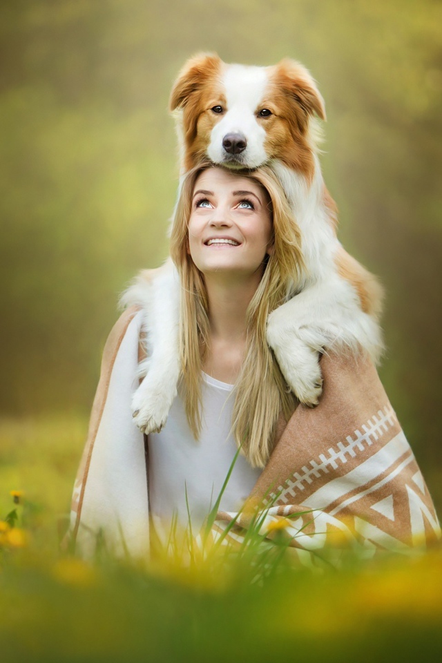 Улыбающаяся девушка с собакой сидят на траве