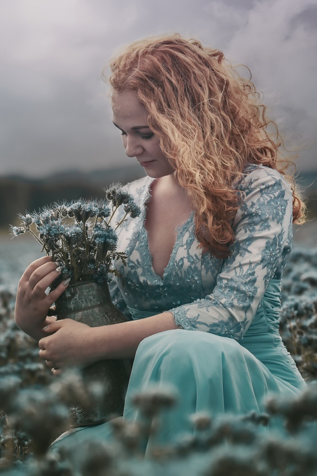 Молодая девушка собирает в кувшин голубые полевые цветы