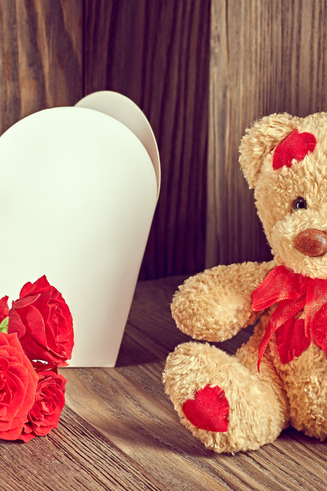 Плюшевый медведь с большим белым бумажным сердцем и красными розами