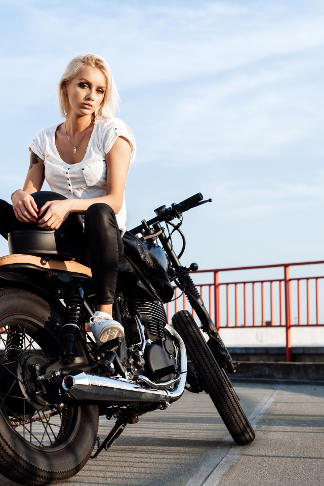 Красивая блондинка сидит на черном мотоцикле