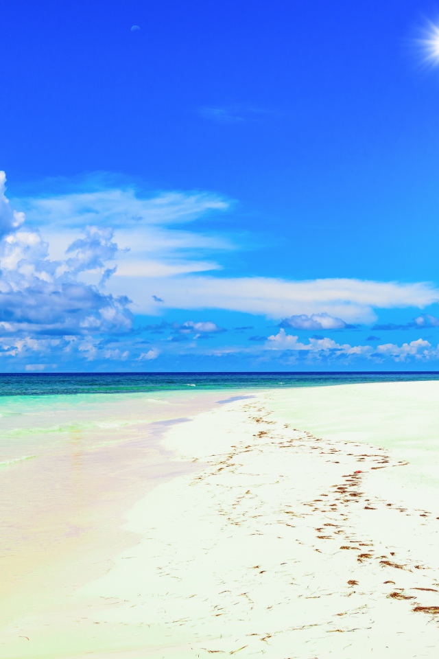 Следы на белом песке на тропическом пляже под красивым голубым небом