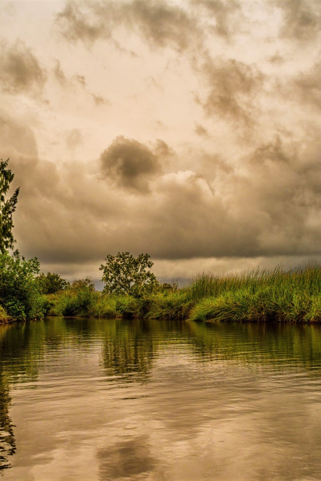 Облака над озером с покрыми зеленой травой берегами