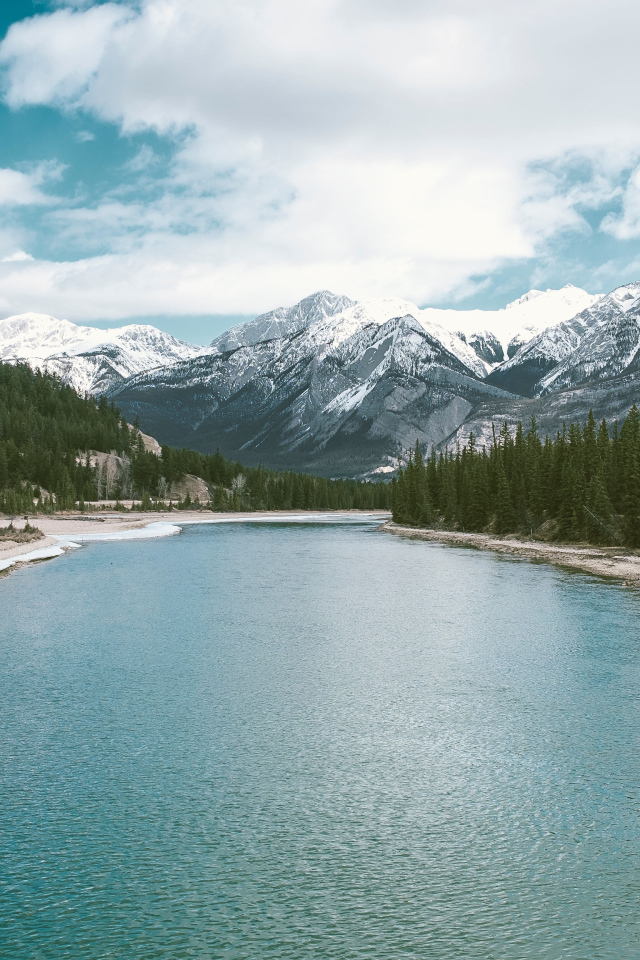 Чистая голубая вода в реке на фоне заснеженных гор 