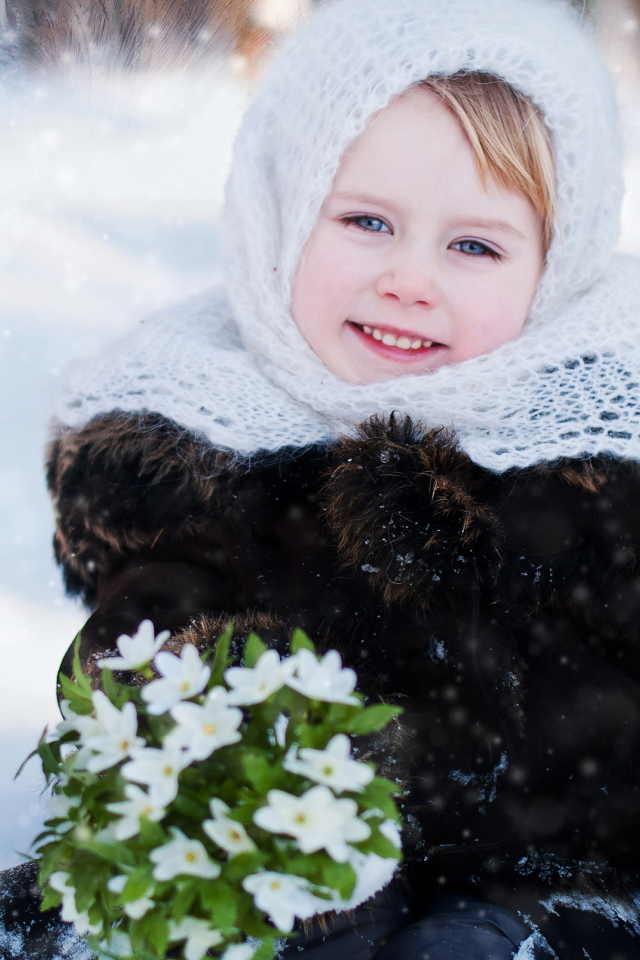 Маленькая голубоглазая девочка с букетом подснежников зимой