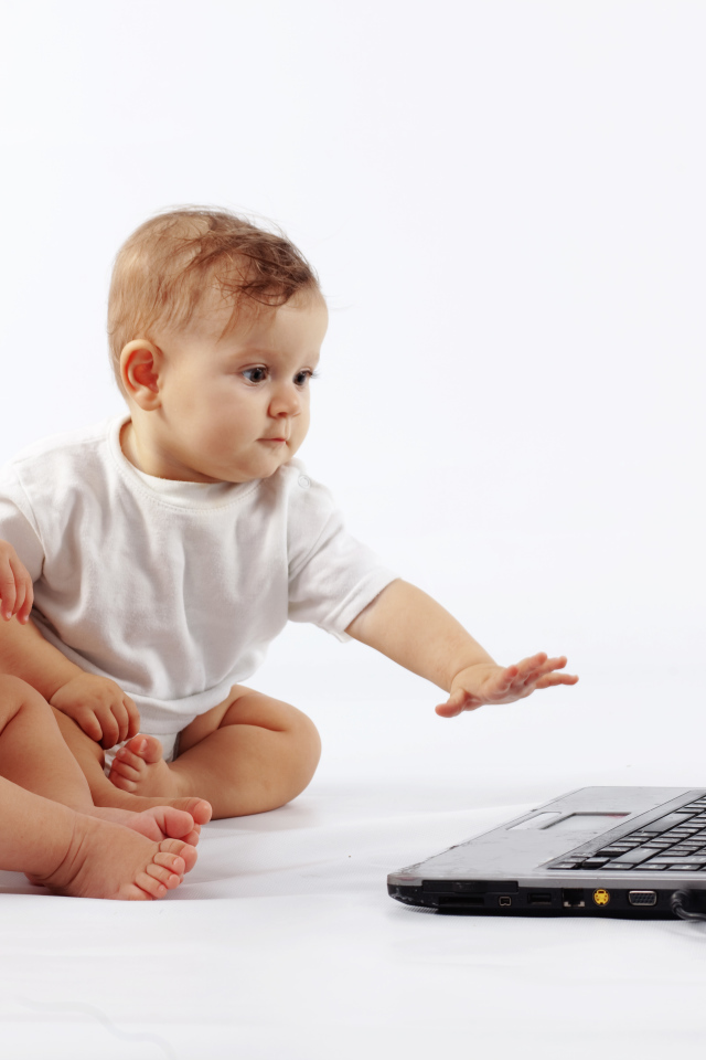 Два младенца перед ноутбуком на белом фоне