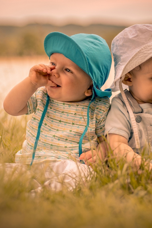 Два милых малыша в зеленой траве летом 