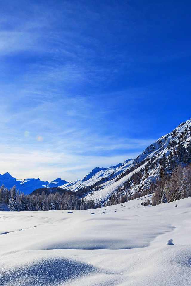 Зимнее солнце в голубом небе над покрытыми снегом горами