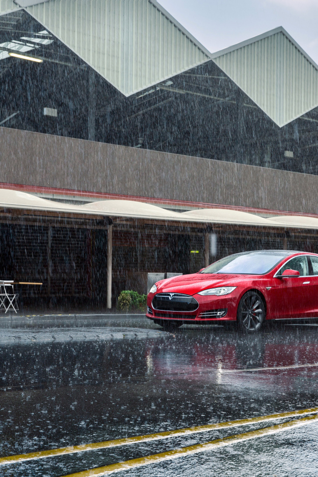Red car Tesla Model S on the road in the rain