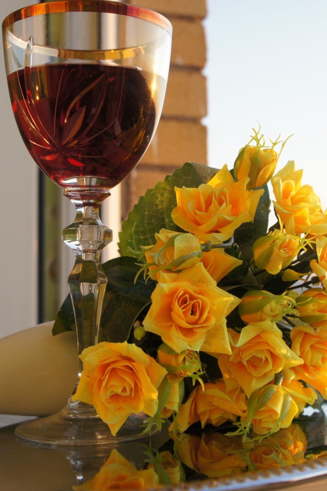 Букет желтых роз на столе с бокалом вина