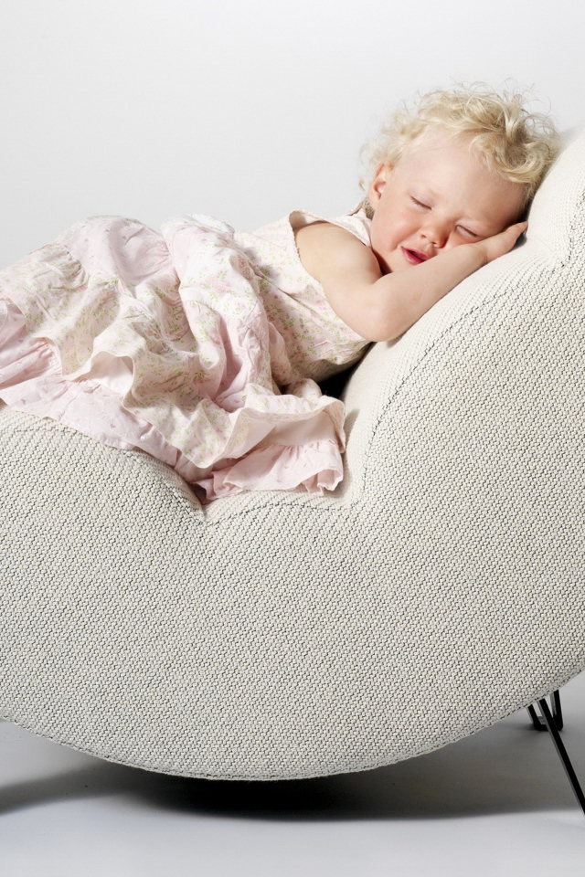 Маленькая девочка в розовом платье спит в кресле