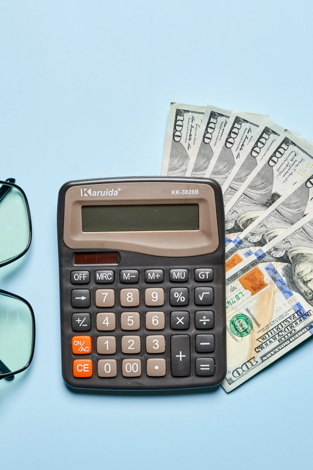 Калькулятор, очки и доллары на голубом фоне