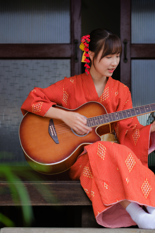 Девушка азиатка в красном кимоно с гитарой в руках