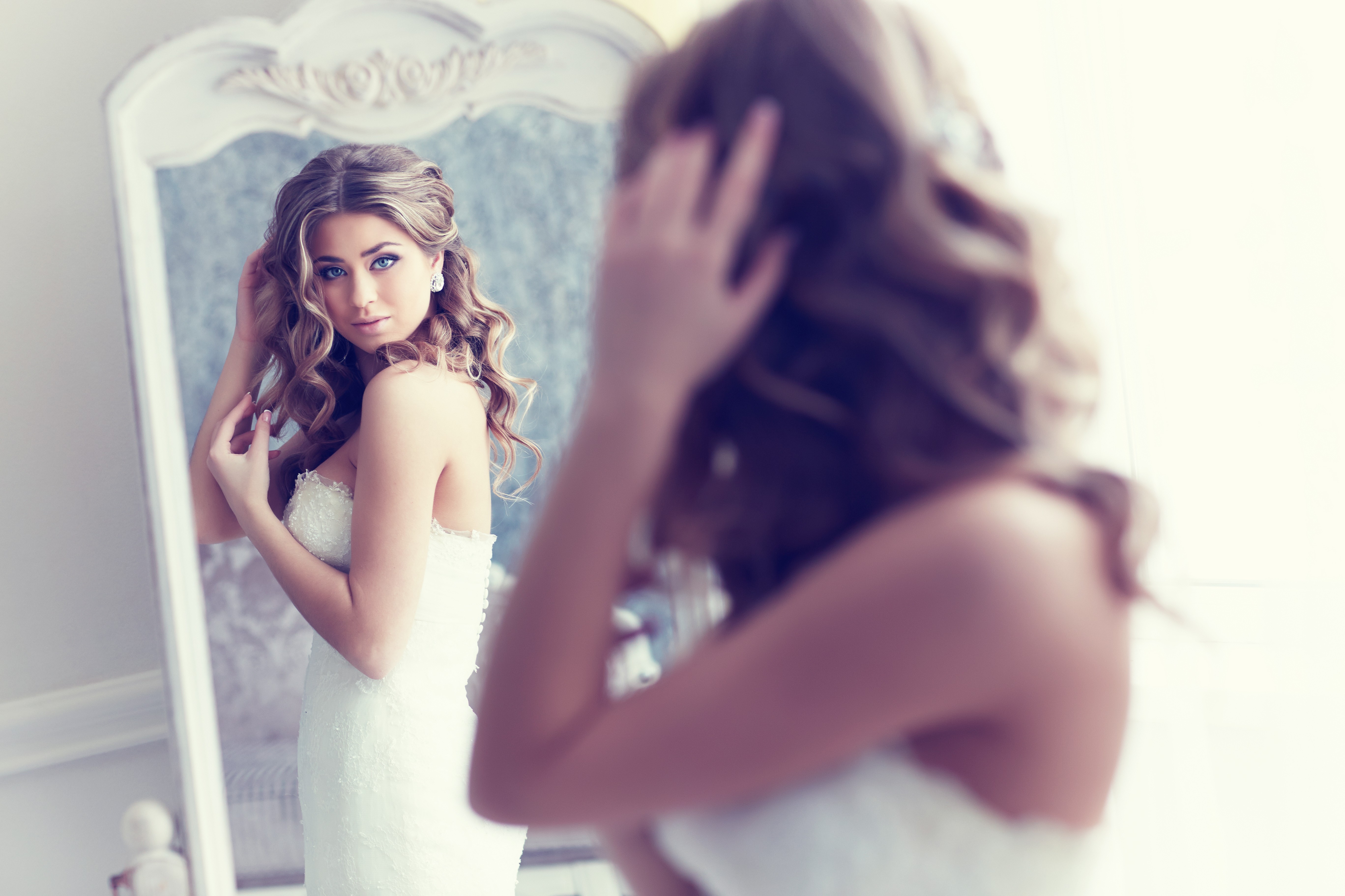 Beautiful girl in a wedding dress looks in the mirror wallpapers and