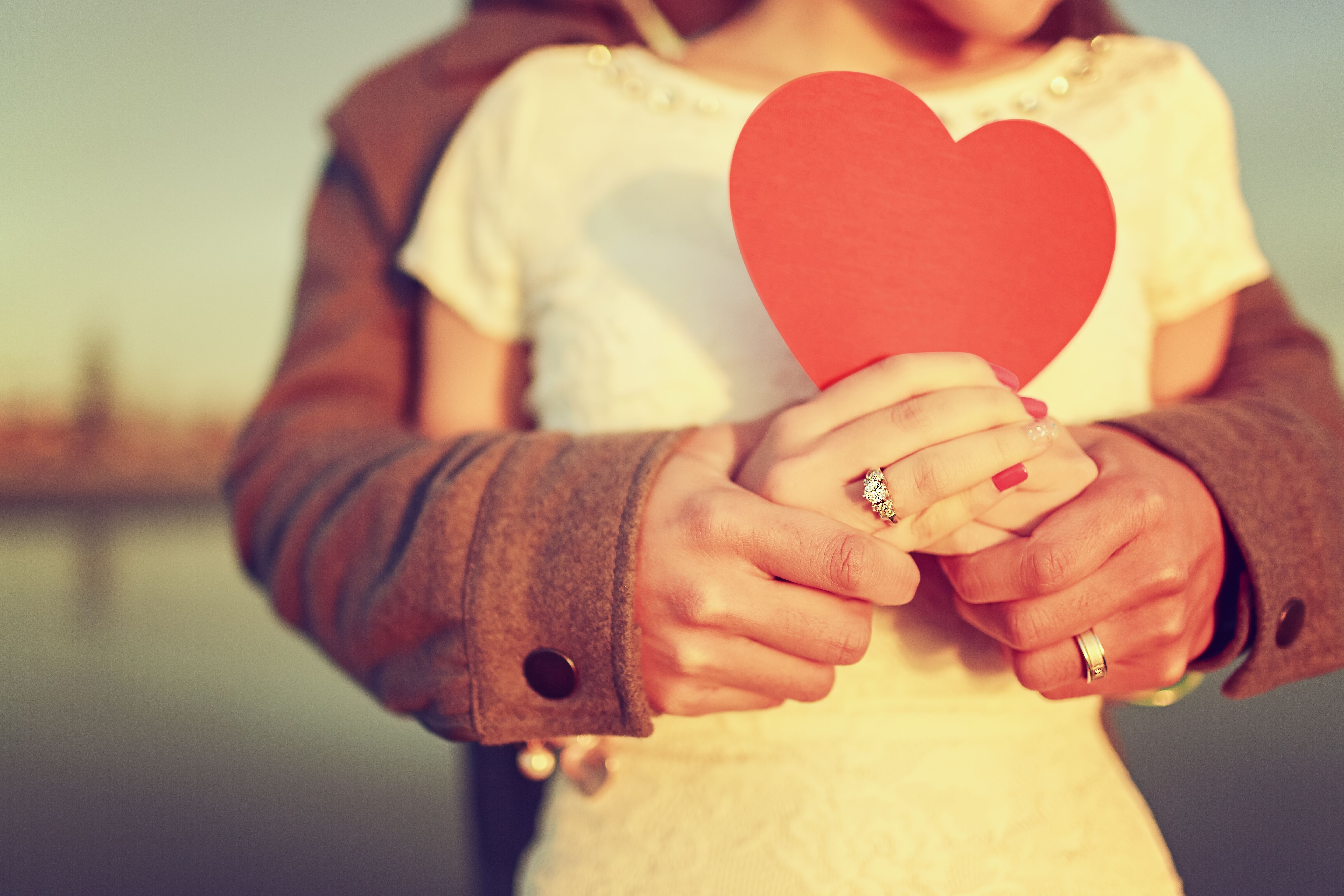 Couple in love holds a red heart of paper wallpapers and images