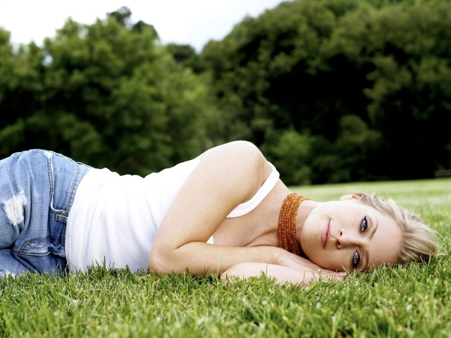 Девушка в джинсах лежит на траве