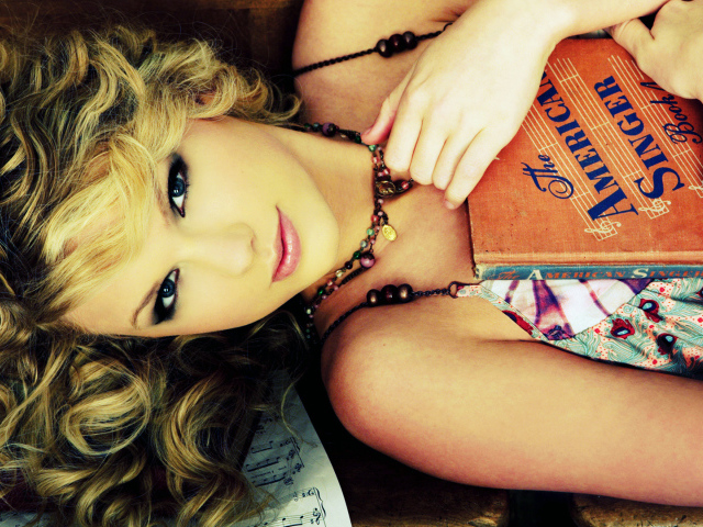 Taylor Swift лежа с своей гитарой