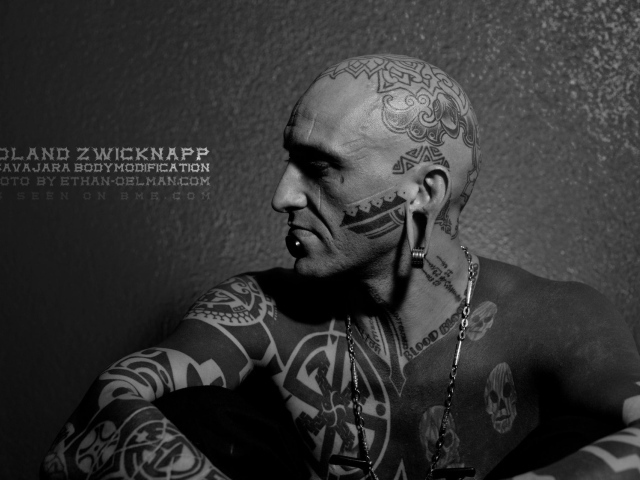 Мужчина с пирсингом в губе и татуировками
