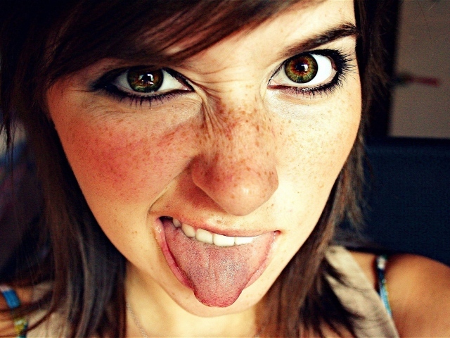 Девушка с веснушками показывает язык