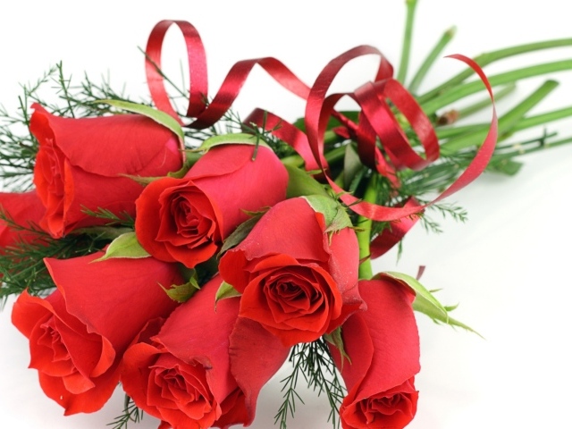 Украшенные красные розы на белом столе на восьмое марта