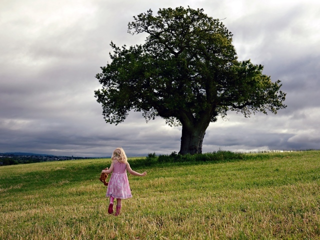 Маленькая девочка бежит к дереву