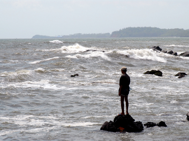 Мужчина ловит рыбу в Гоа